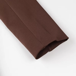 Détail du blazer marron montrant la texture du tissu sergé et les coutures propres du poignet