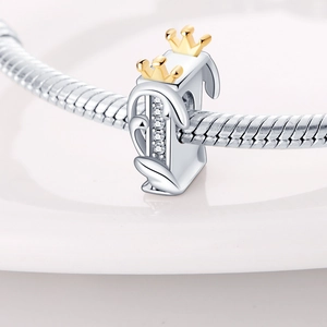 Macro detail of silver letter I charm with gold crown and zircon on a snake chain bracelet