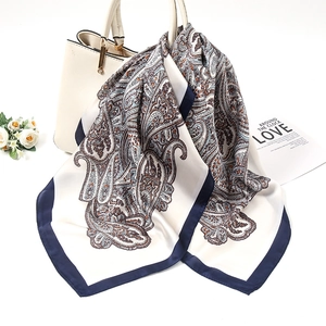 Detail of vintage paisley silk scarf tied to a leather handbag with soft silk luster