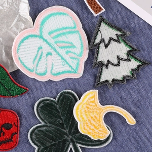 Assorted colorful embroidered patches with leaf and cherry designs on denim background