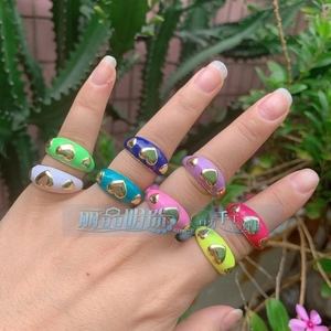 Macro detail of colorful enamel copper rings with embossed gold hearts on a hand