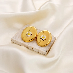 Golden oval stud earrings featuring delicate white daisy motif on elegant stone surface