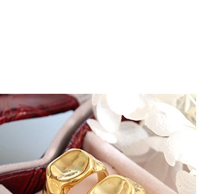 Detailed close-up of a wide gold-plated stainless steel irregular ring in a red leather box