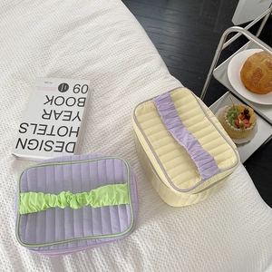 Close-up of quilted makeup bags with ruched handles in purple and yellow colors