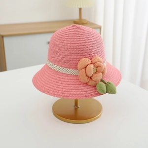 Detailansicht eines rosa Strohhuts mit Stoffblume und gepunktetem Band auf einem Ständer