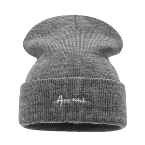 Bonnet en tricot gris foncé avec une broderie cursive blanche sur le revers