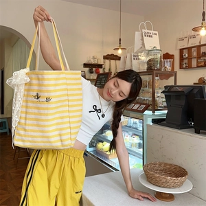 Detail of yellow striped canvas tote bag with lace bow and bee embroidery detail