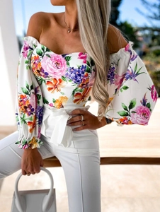 Detail of floral puff sleeve top paired with high-waisted white pants in outdoor light