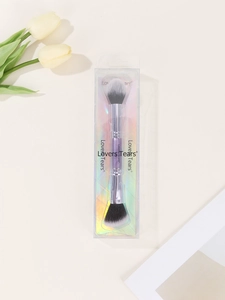 Detailed view of dual-ended makeup brush with purple handle in holographic packaging