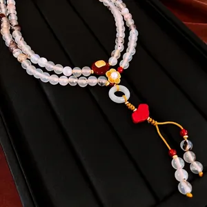 Elegant Chinese style pearl agate necklace with gold flower pendant on a black jewelry tray
