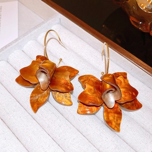 Macro shot of amber resin flower earrings with gold hooks inside a white jewelry box