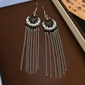 Detail of silver bamboo flower earrings with long tassels and black beads on brown velvet