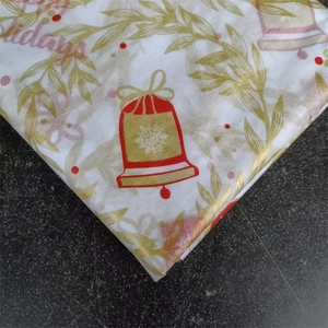 Close-up of Christmas tissue paper with red bells and gold foliage for gift wrapping
