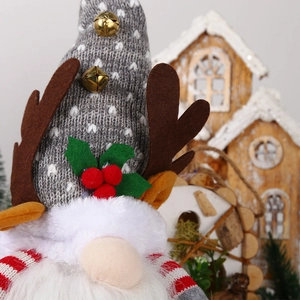 Close-up of a lighted Christmas gnome with a gray knit hat, antlers, and festive berries