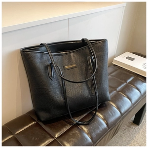 Detail of black tote bag showing fine leather texture and gold FASHION & BAGS plaque