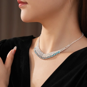 Macro detail of silver tassel necklace with sparkling clear and blue rhinestones on neck