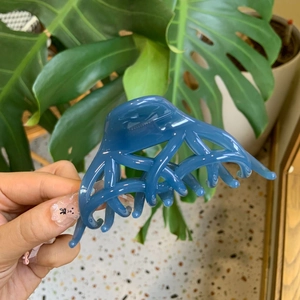 Dettaglio della molletta per capelli in resina blu con design a incrocio