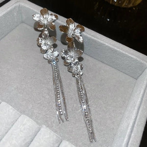 Macro detail of silver flower tassel earrings with sparkling rhinestones in a jewelry box