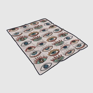 Detail of soft flannel blanket featuring a colorful exotic evil eye pattern with black edging