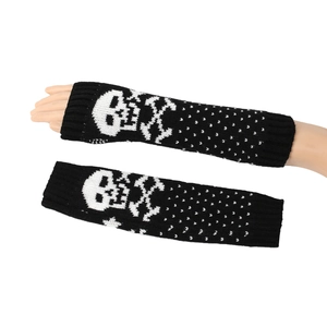 Close-up of black knitted arm warmers featuring white skull and crossbones and polka dots