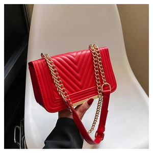 Detail of red quilted leather handbag featuring V-pattern stitching and gold chain strap