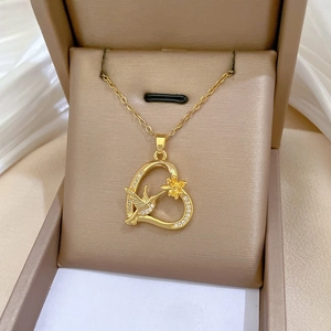 Macro shot of gold hummingbird heart necklace with white zircons in a premium jewelry box