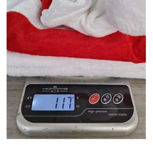 Weight measurement of red and white striped plush Christmas hat showing 117g on scale
