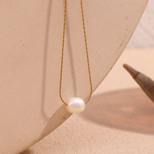 Detail view of a dainty 18K gold-plated chain with a single white oval pearl pendant