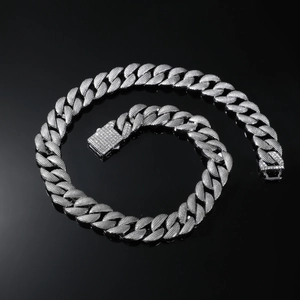 Detail of 16mm silver Cuban link chain with encrusted rhinestones on black reflective surface