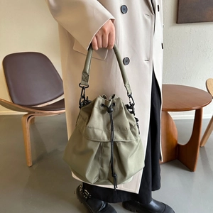 Détail du sac seau en nylon vert armée avec cordons noirs et accessoires en métal mat
