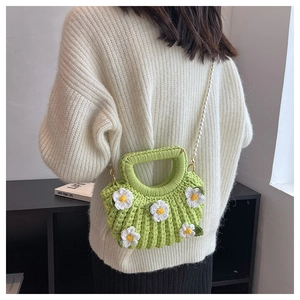 Detail of green handmade crochet daisy bag with pearl strap worn over white sweater