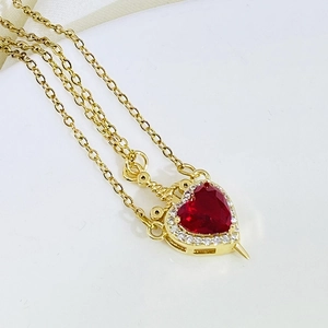 Macro shot of gold sword heart pendant with red gem and zircon micro-inlay detail