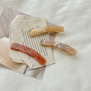 Three elegant tortoiseshell hair clips in amber and reddish brown on natural linen