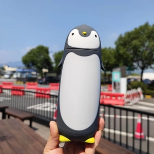Close-up of a cute penguin-shaped vacuum flask in dark grey and white for outdoor use