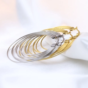 Macro detail of 50mm gold and silver multi-strand stainless steel hoop earrings on silk