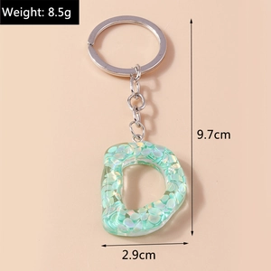 Detailed view of resin letter D keychain with green glitter flakes and silver chain