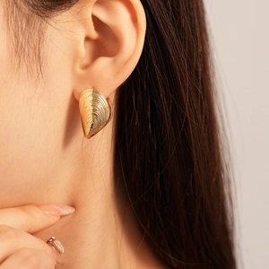 Elegant gold shell-textured hoop earring with metallic finish on model ear