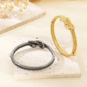 Minimalist knot-style open bracelets in gold and silver finish on a stone platform