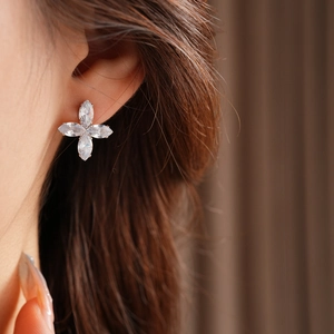Vue macro d'une boucle d'oreille fleur argentée à quatre pétales avec zircone au lobe