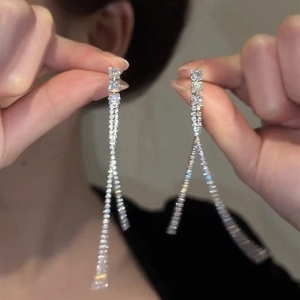 Détail de boucles d'oreilles pendantes argentées avec strass brillants à la main