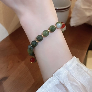 Macro detail of multicolored green and red beaded bracelet with jade-like texture on wrist