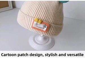 Close-up of beige knit baby hat with ribbed texture and cute sun character patch