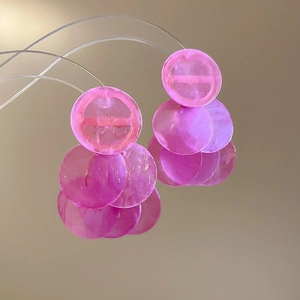 Macro detail of pink translucent shell earrings with a layered round tassel design