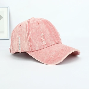 Close-up of distressed vintage pink denim baseball cap with frayed edges and washed finish