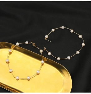 Detail of handcrafted gold wire hoop earrings with elegant white pearls on a tray