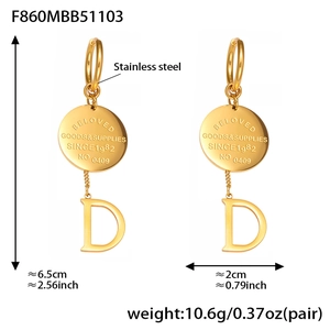 Détail de boucles d'oreilles en acier inoxydable doré avec disque gravé et lettre D