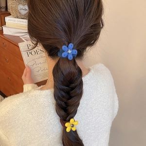 Chouchous fleurs bleues et jaunes avec strass présentés sur une coiffure tressée