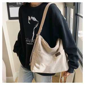 Détail du sac hobo en velours côtelé beige avec poche latérale et étiquette mode en cuir