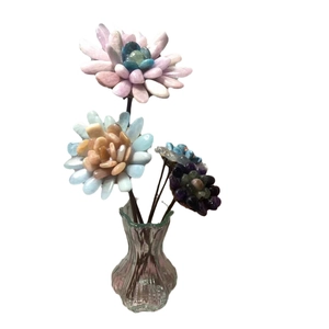 Handmade crystal tumbled flower ornaments in a wave glass vase on a clean white background