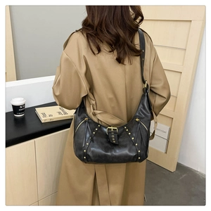 Detail einer Vintage Halbmond Umhängetasche in Schwarz mit goldenen Nieten am Modell